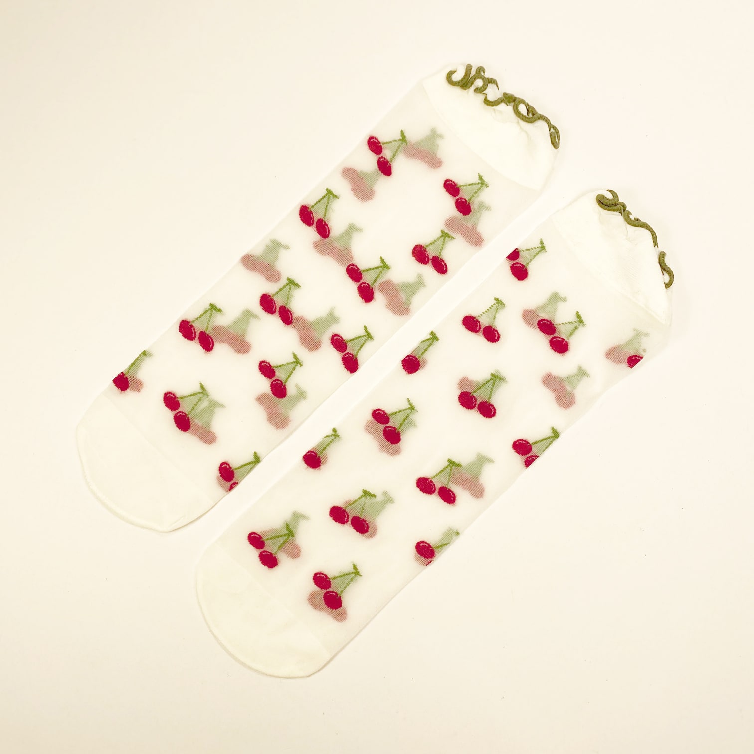 Sheer socks with red cherry embroidery and green stems on transparent mesh