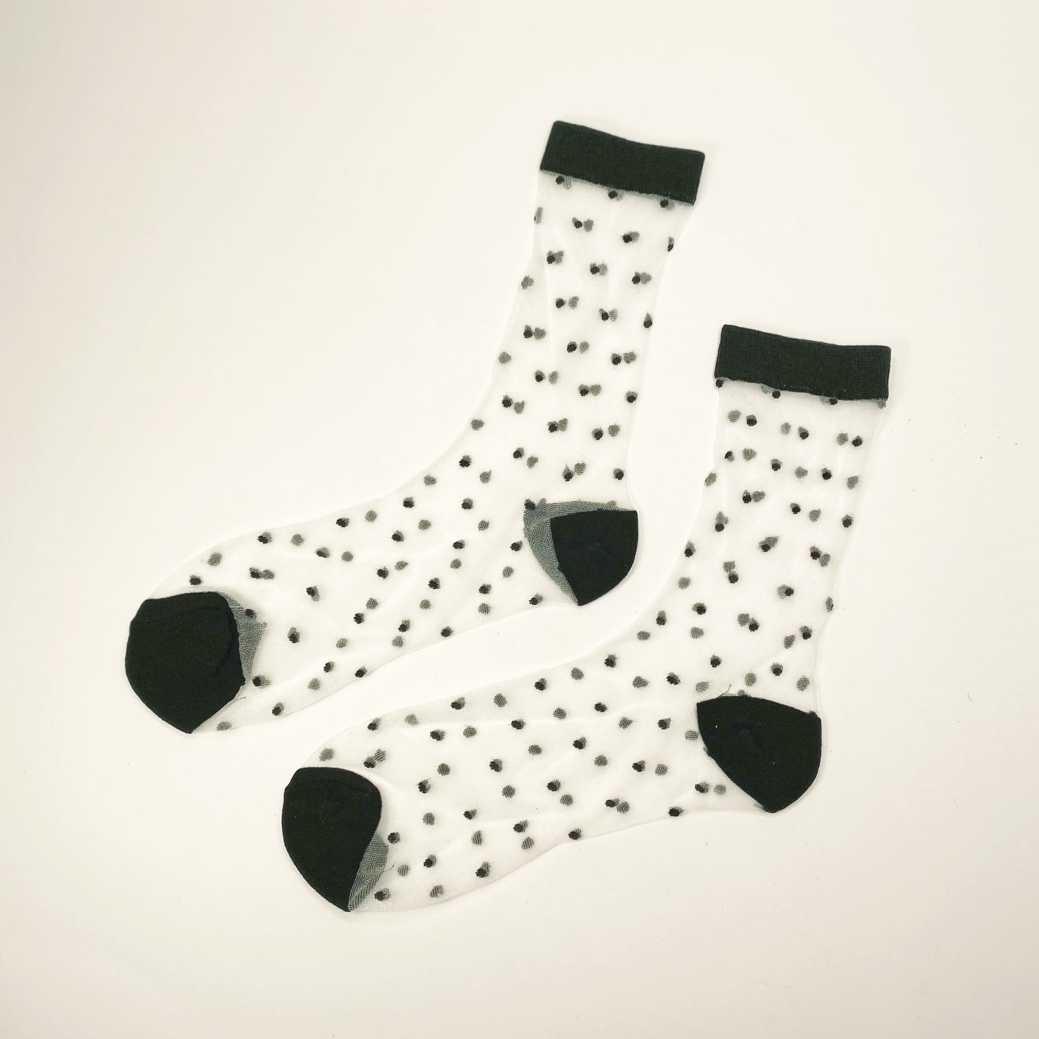 Flat view of transparent socks with small raised black dots and black toe heel and cuff