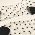 Flat view of transparent socks with small raised black dots and black toe heel and cuff
