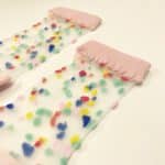 Transparent socks with pink toe heel and cuff scattered with fuzzy multicolor dots