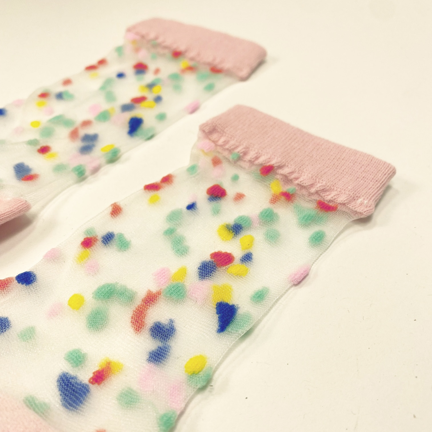 Transparent socks with pink toe heel and cuff scattered with fuzzy multicolor dots