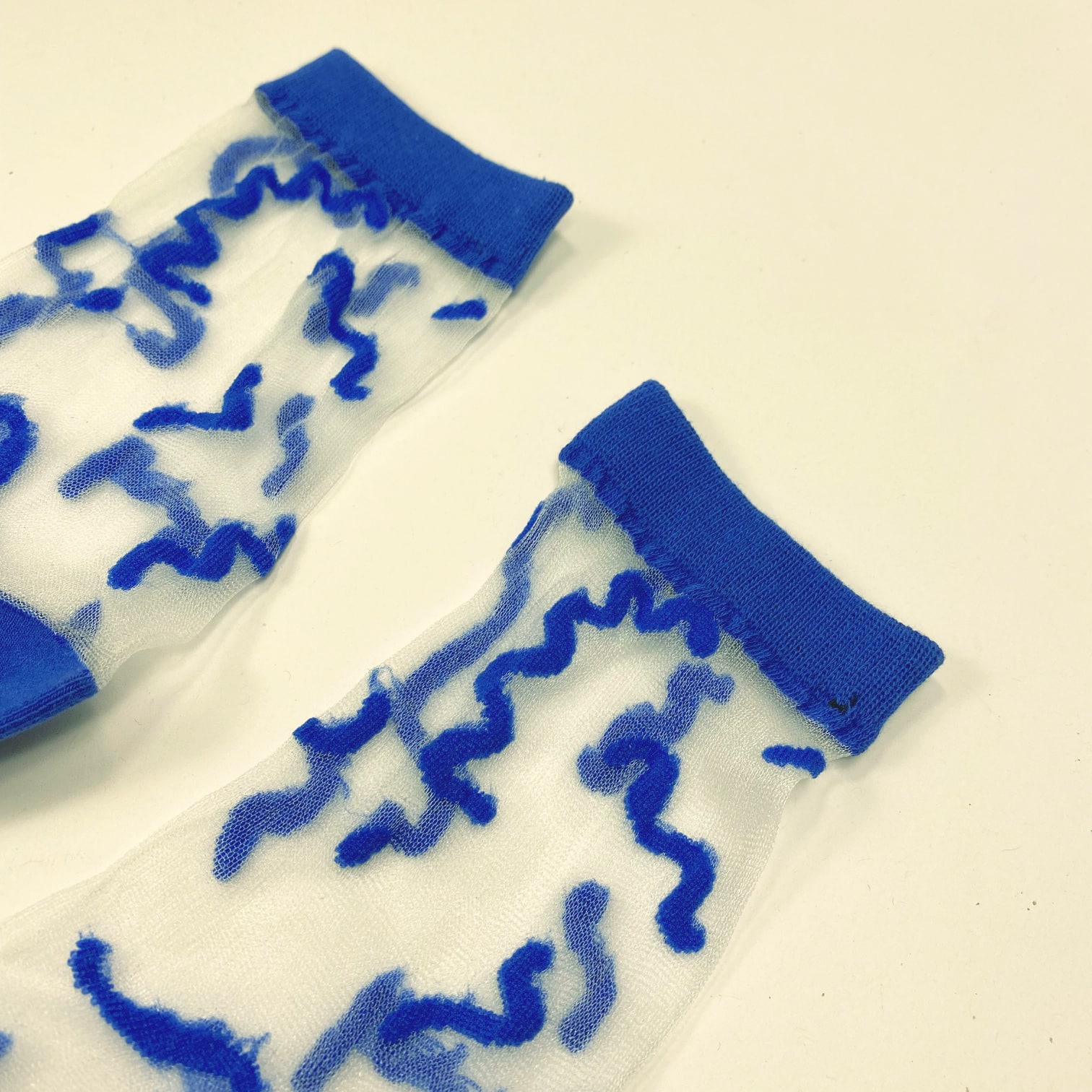 Pair of sheer socks with abstract blue squiggle lines and blue accents