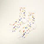 Sheer white socks with multicolored dots and white toe and cuff on a white background