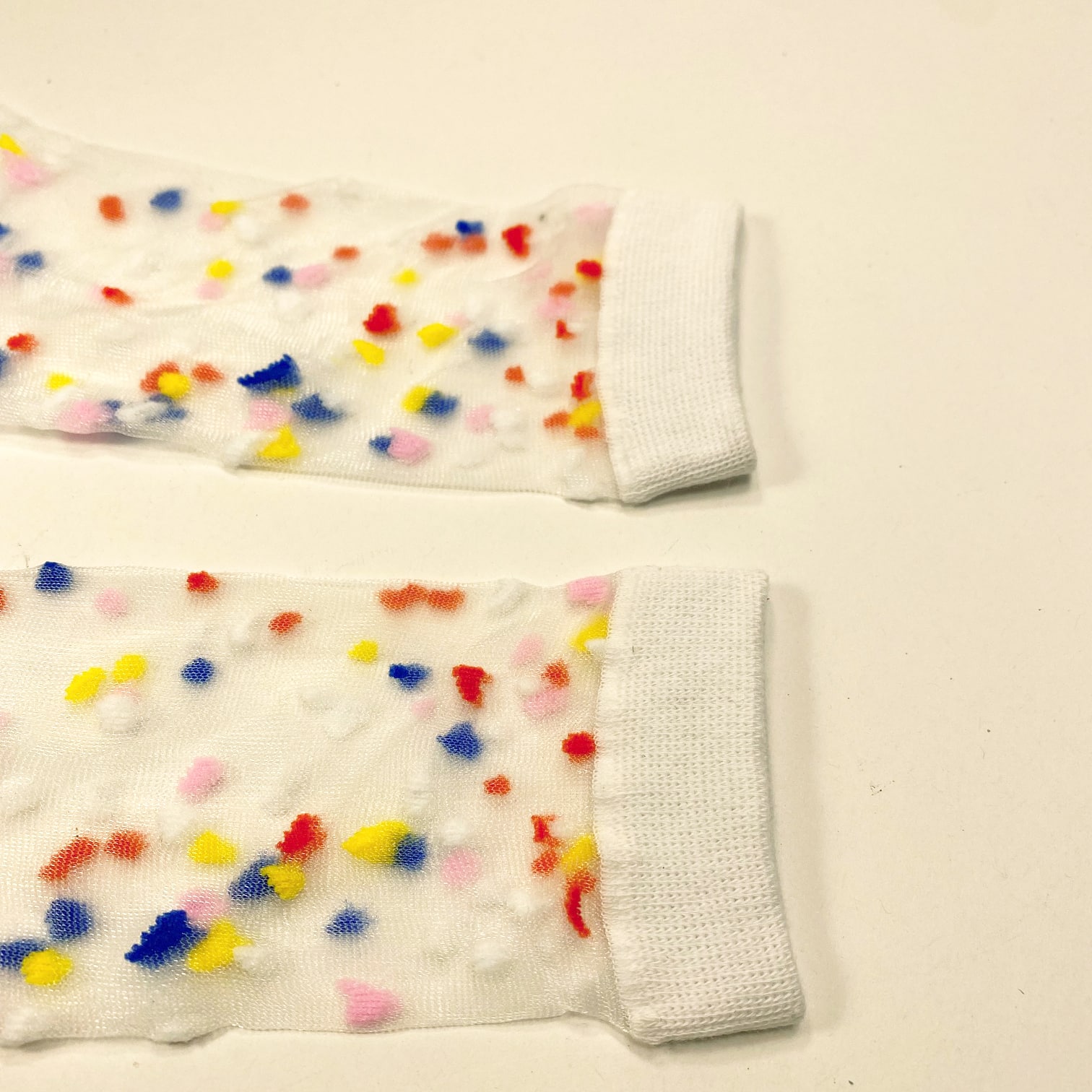 Close-up of colorful confetti details on sheer socks with white cuff