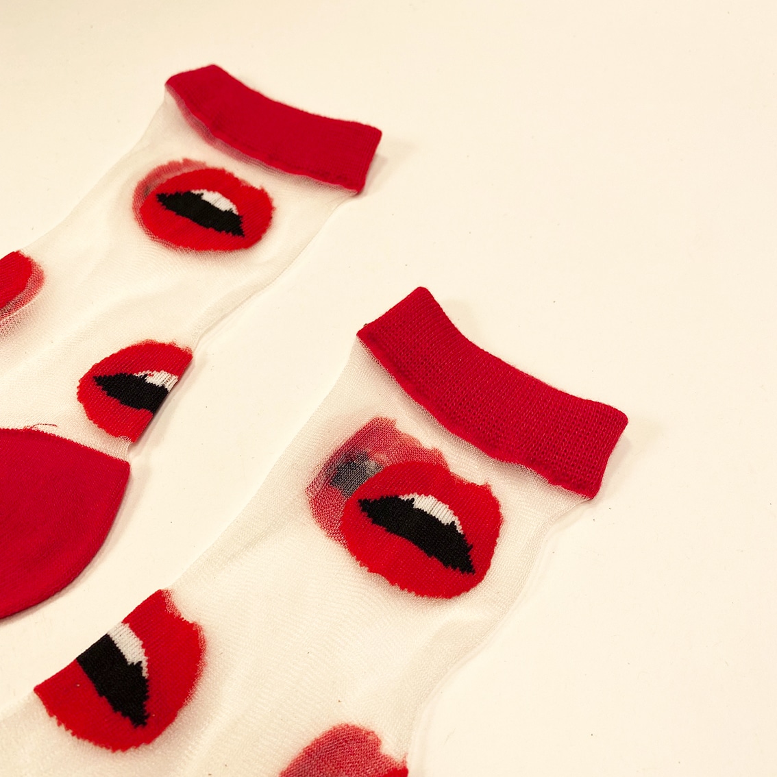 Detailed view of red lips pattern on sheer socks with red cuff