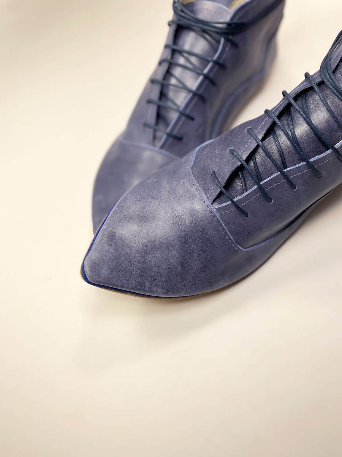 Angled close-up of blue leather pointed-toe lace-up shoes, handmade in Italy