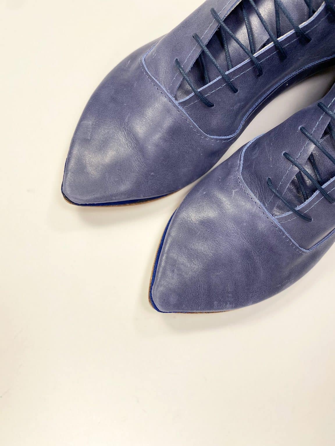 Close-up of handcrafted blue leather pointed-toe lace-up shoes, Italian artisan design