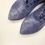 Close-up of handcrafted blue leather pointed-toe lace-up shoes, Italian artisan design