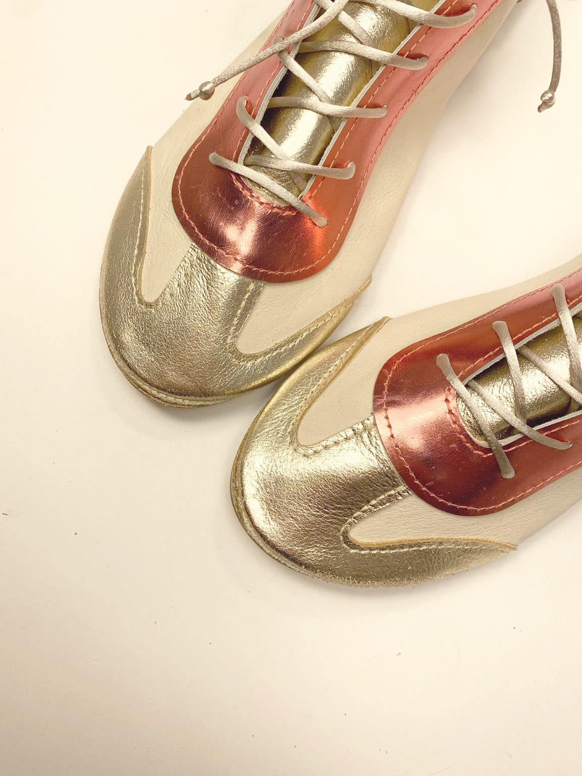 Close-up of metallic gold and coral Italian leather trainers