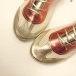 Close-up of metallic gold and coral Italian leather trainers