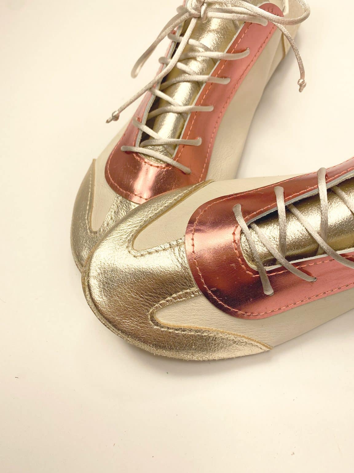 Handmade trainers in metallic gold and coral Italian leather angled view