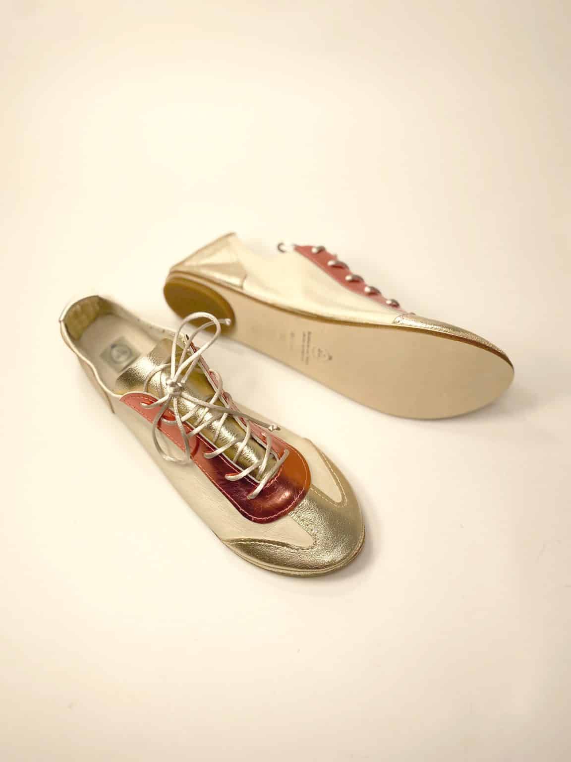 andmade Italian leather trainers in metallic gold and coral showing soles